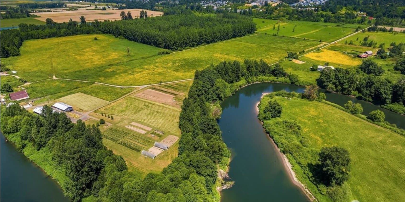 Aerial view of the Wild Roots property near Duvall, WA — open fields and pasture inside a bend of the river