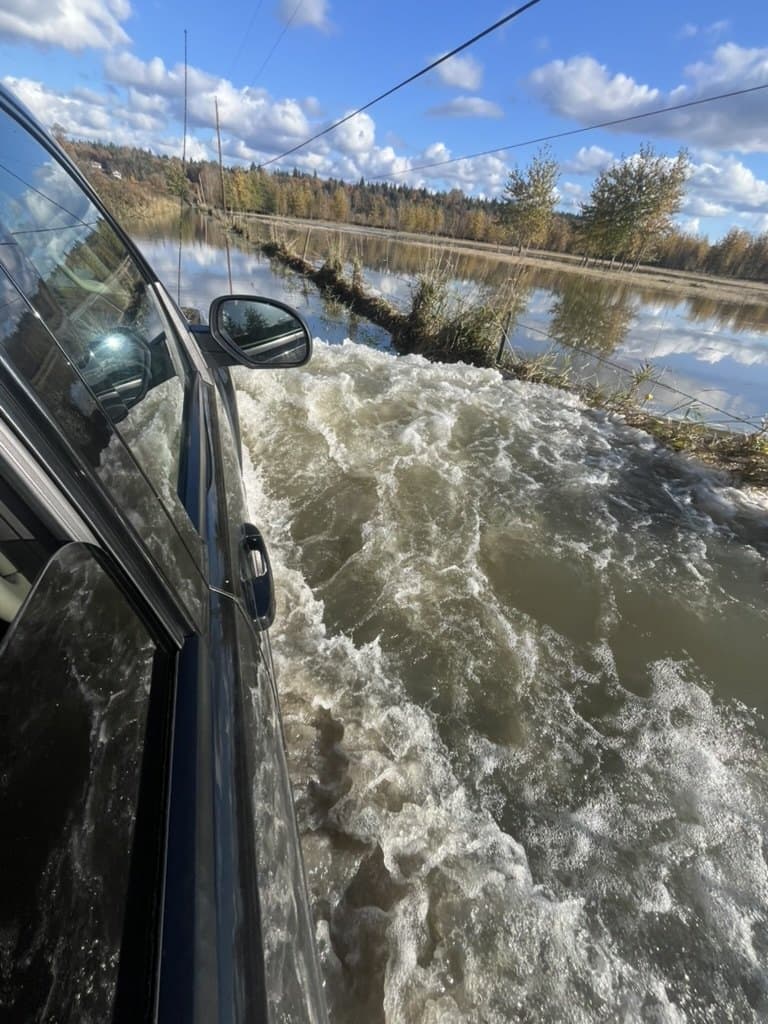 Driving across a partly submerged road during the January 2026 floods, water churning past the truck